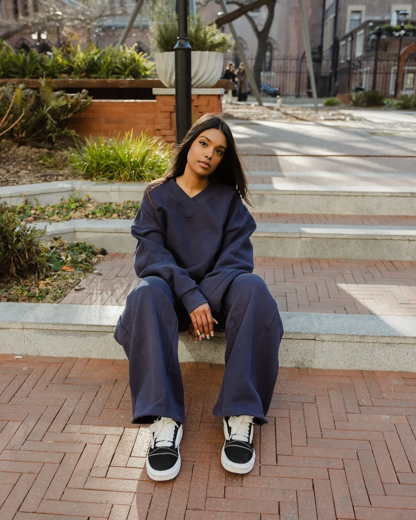 Woman seated on steps in a navy V-neck lounge sweatshirt and wide-leg pants