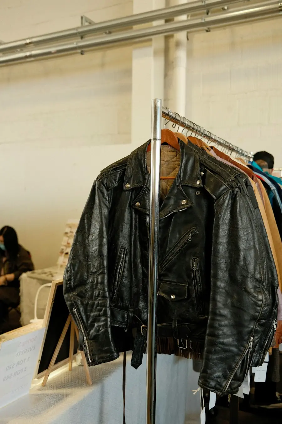 A black leather jacket on a clothes rack